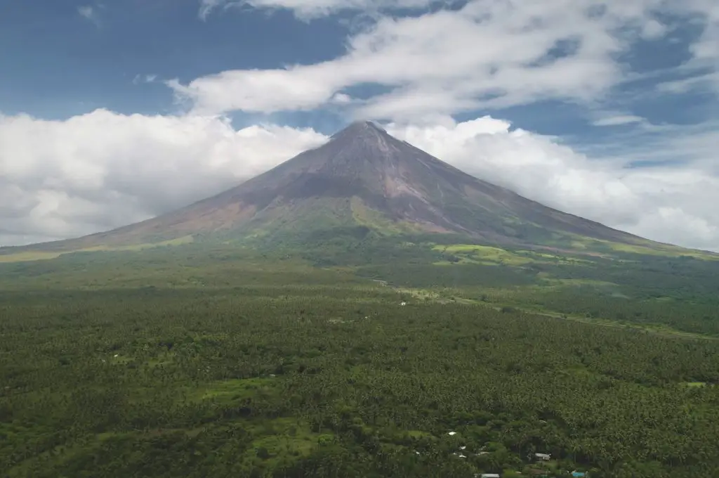 Closeup Philippines volcano haze eruption aerial. Green grass landmark of Mayon mountain with hiking path. Legazpi countryside mount. Nobody nature landscape at mist. Cinematic drone shot